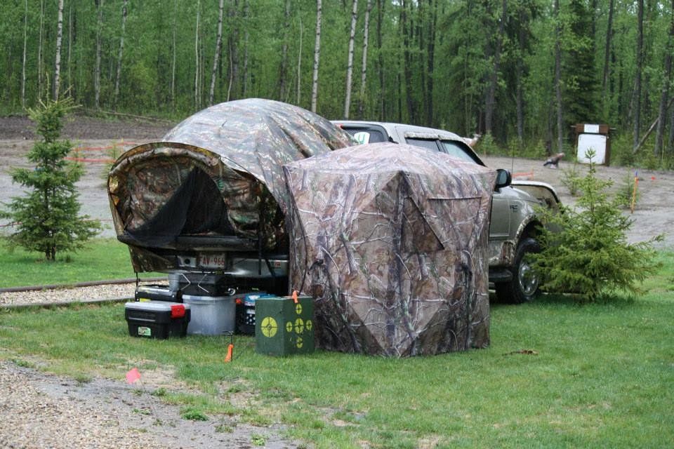A truck is parked next to a tent in the grass.