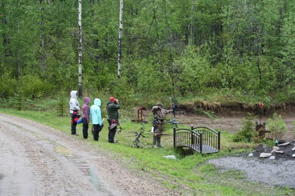 A group of people are standing on the side of a dirt road.