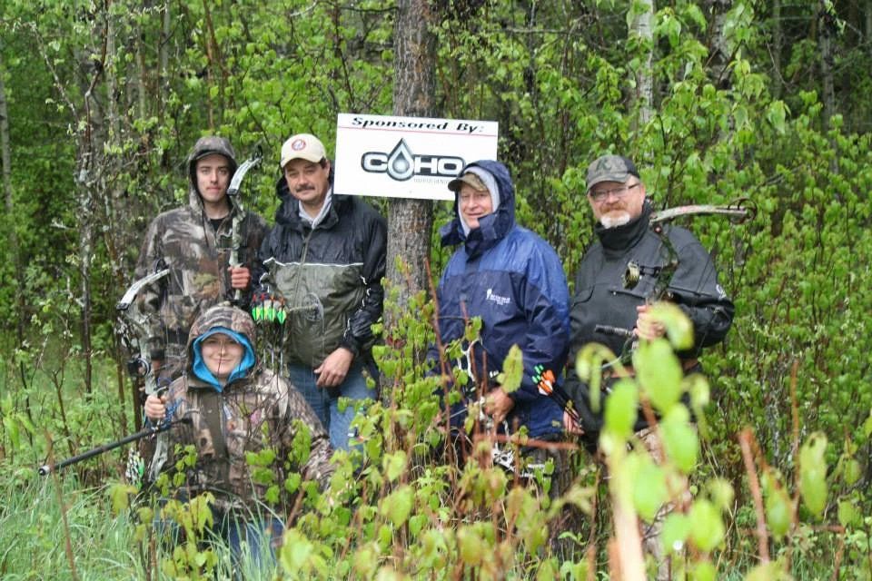 A group of people are posing for a picture in the woods.
