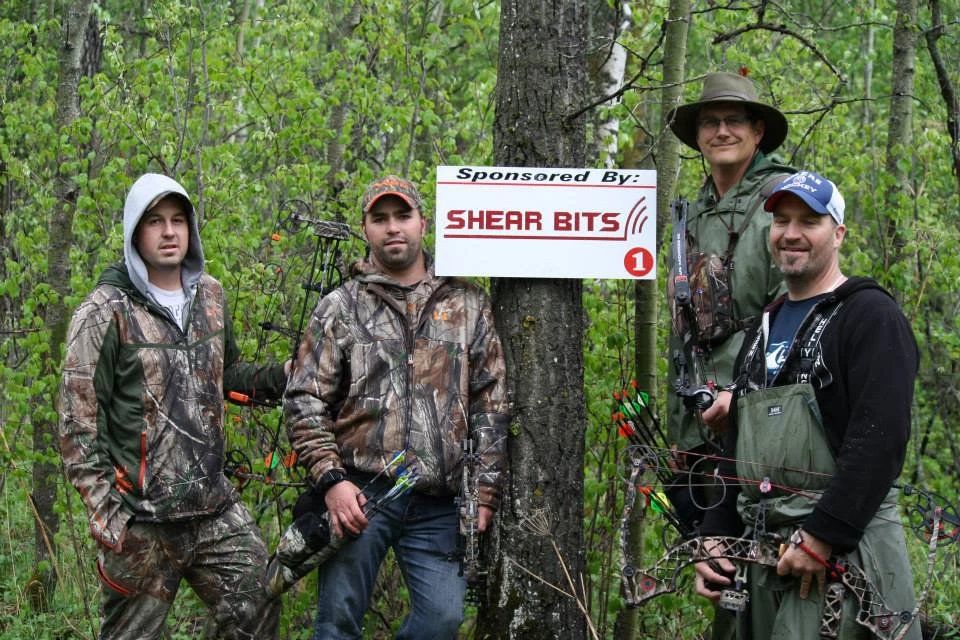 A group of men are standing in front of a sign that says shear bits.