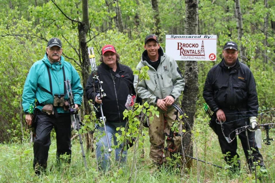 A group of men are standing in the woods holding bows and arrows.