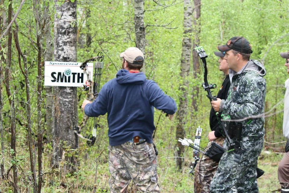 A group of men are standing in the woods holding bows and arrows.
