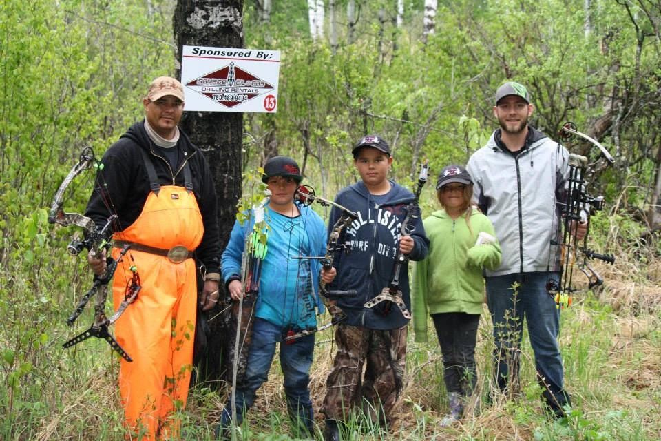 A group of people are standing in the woods holding bows and arrows.