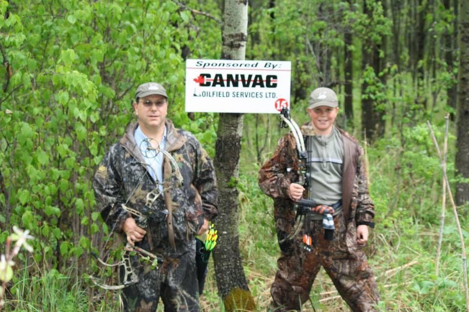 Two men are standing next to a sign that says canvac