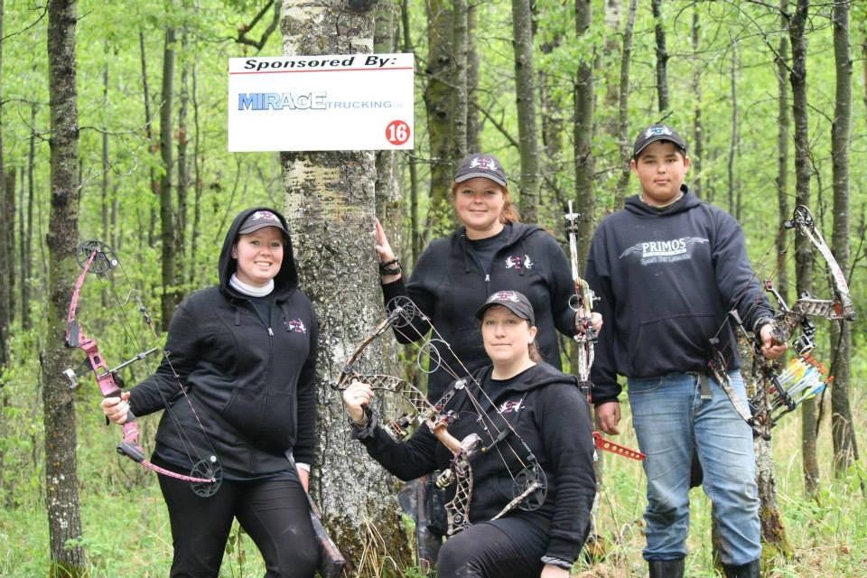 A group of people are standing in the woods holding bows and arrows.