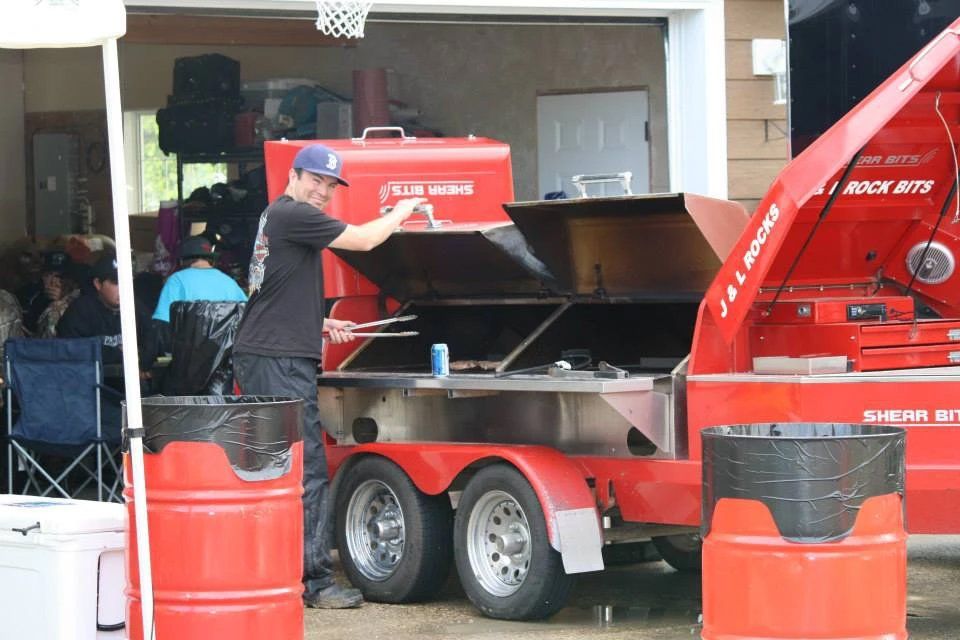 A man is standing next to a red trailer with the hood open