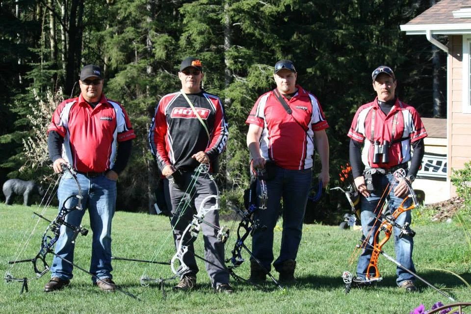 A group of men are standing in a field holding bows and arrows.