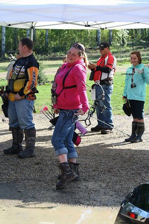 A group of people are standing under a tent holding bows and arrows.