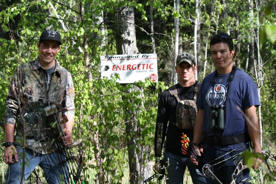 Three men are standing in front of a sign that says energetic