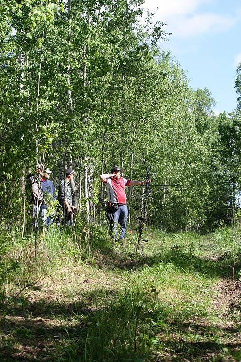 A group of people are standing in a forest holding bows and arrows.