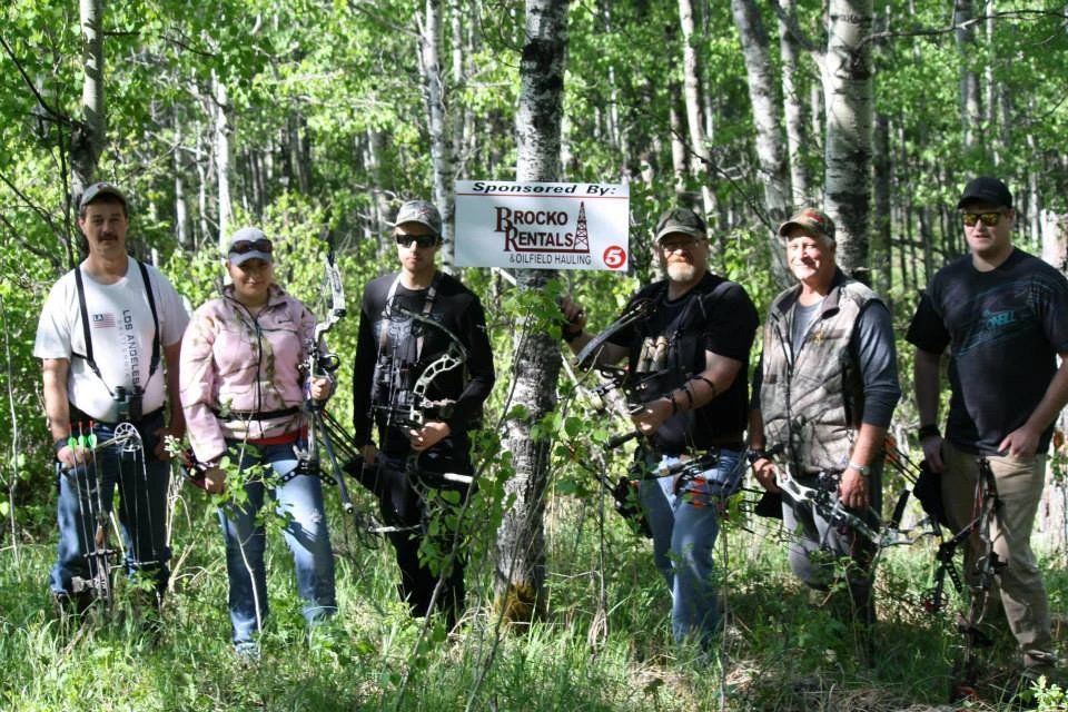 A group of people are standing in the woods holding bows and arrows.