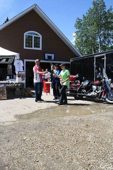 A group of people are standing in front of a building and motorcycles.
