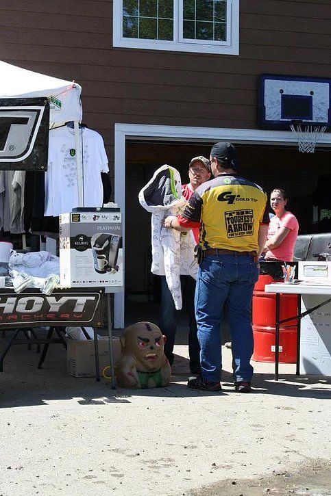 A man in a yellow shirt is standing in front of a table with a monkey on it.
