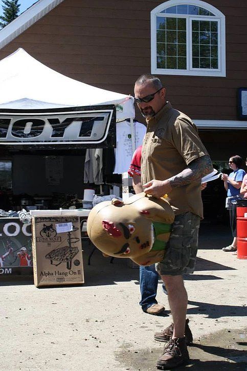 A man is holding a stuffed animal in front of a sign that says coyt