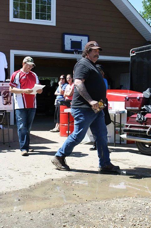 A man is walking towards a motorcycle in front of a garage.