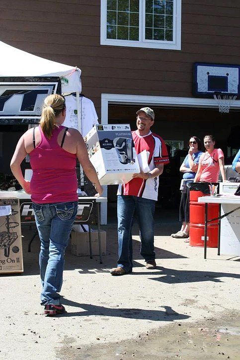 A woman in a pink tank top is standing next to a man holding a box.
