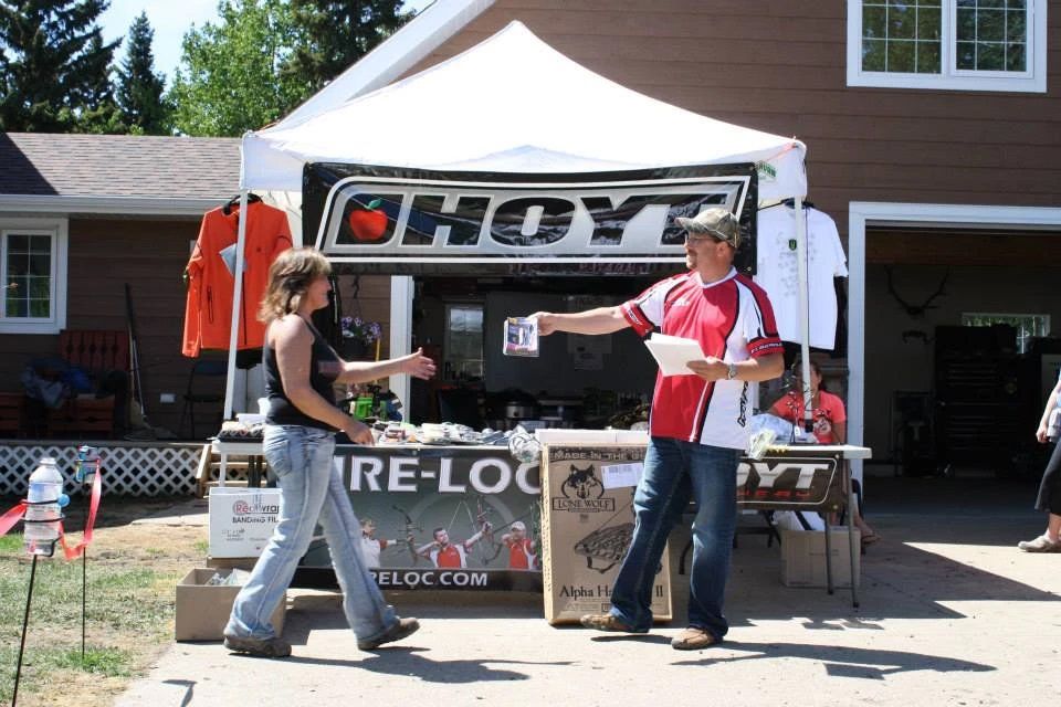 A man and woman are standing in front of a choyt tent