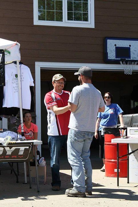 A man in a red shirt is shaking hands with another man