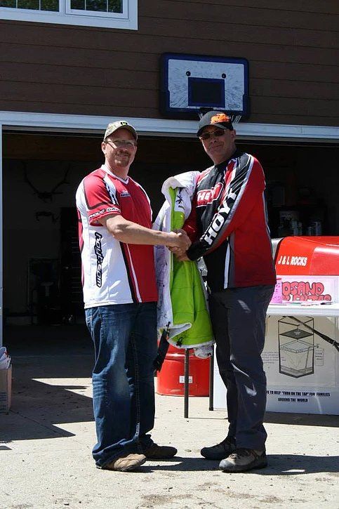 Two men are shaking hands in front of a basketball hoop.