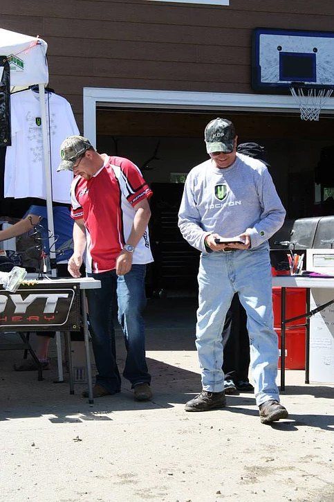 Two men are standing in front of a table in front of a garage