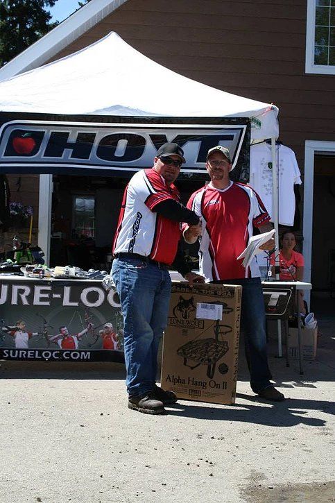 Two men shaking hands in front of a tent that says ' ohyt ' on it