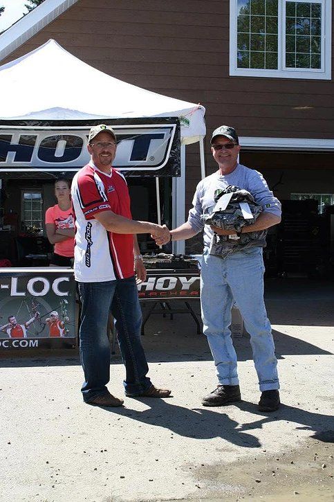 Two men shaking hands in front of a sign that says hoy