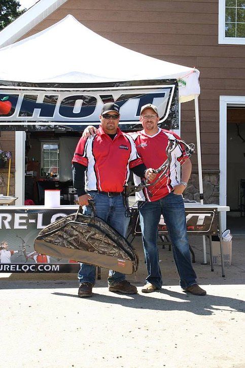 Two men are standing next to each other in front of a tent.