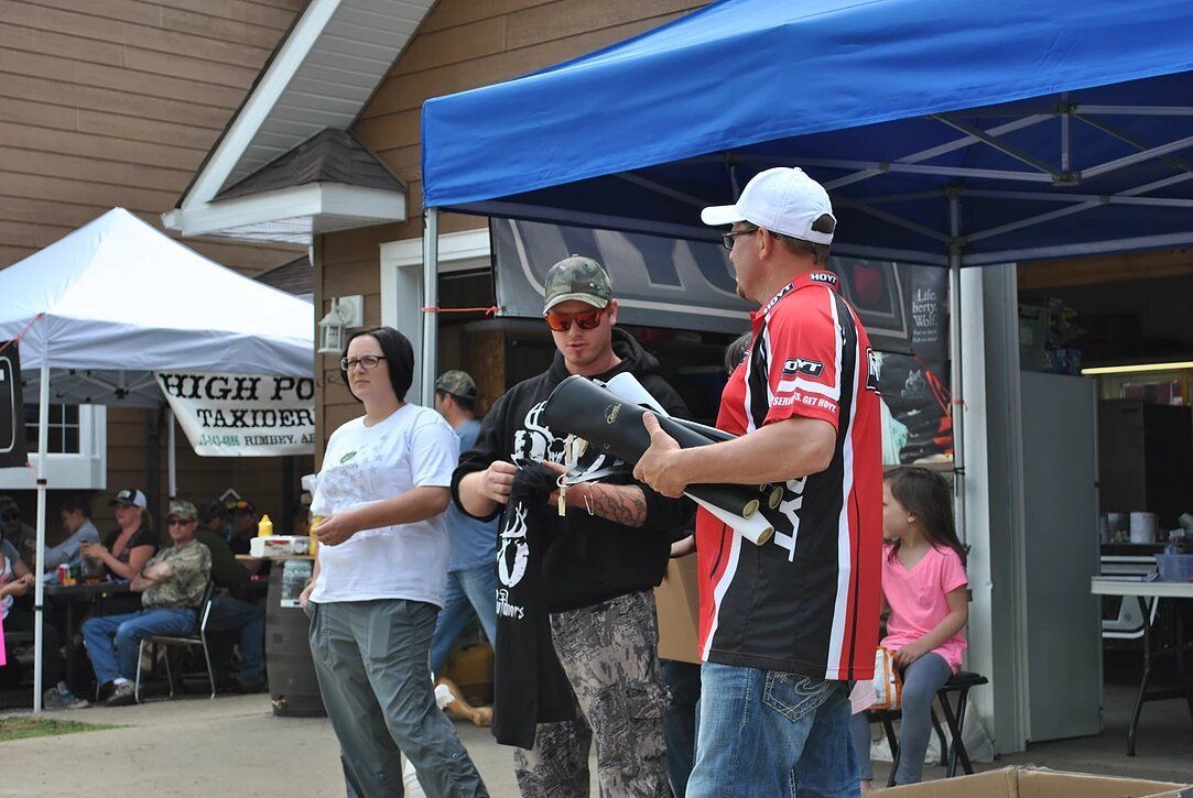 A group of people are standing in front of a blue tent.
