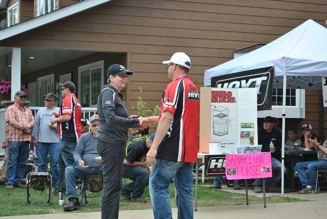 A man is shaking hands with another man in front of a group of people.