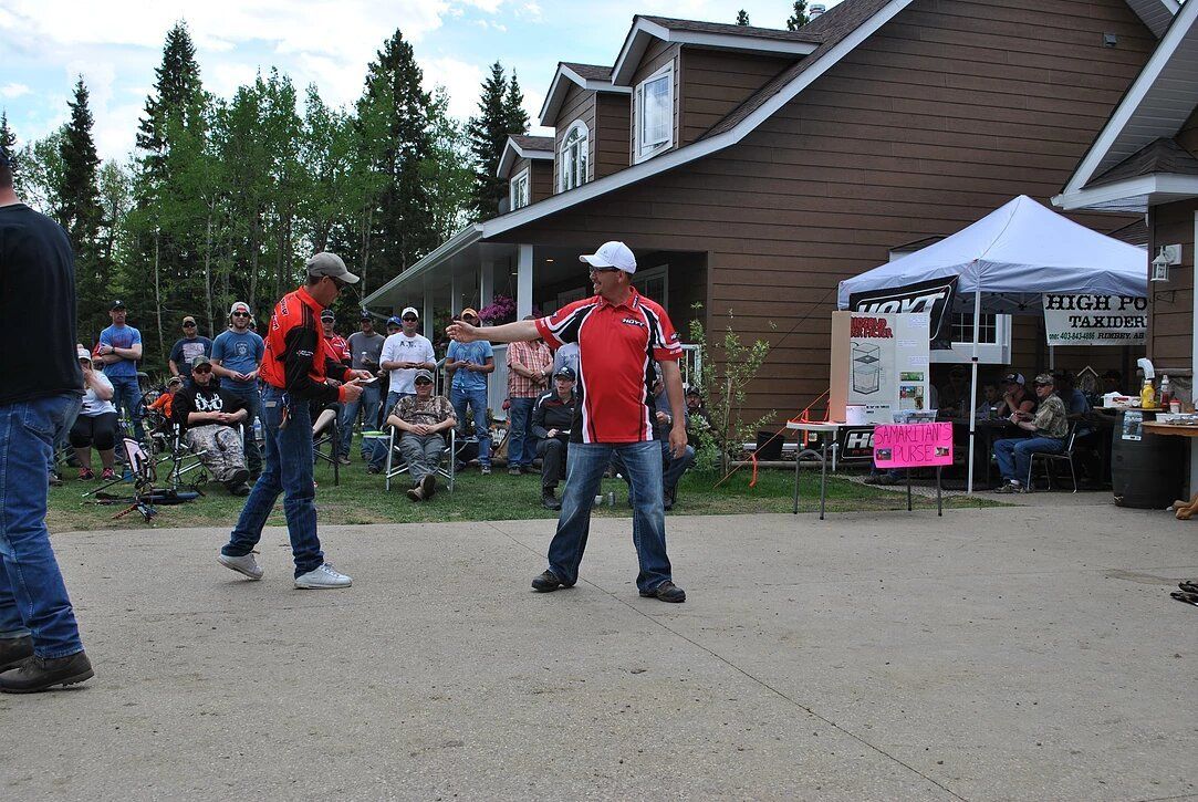 A man in a red shirt is dancing in front of a house