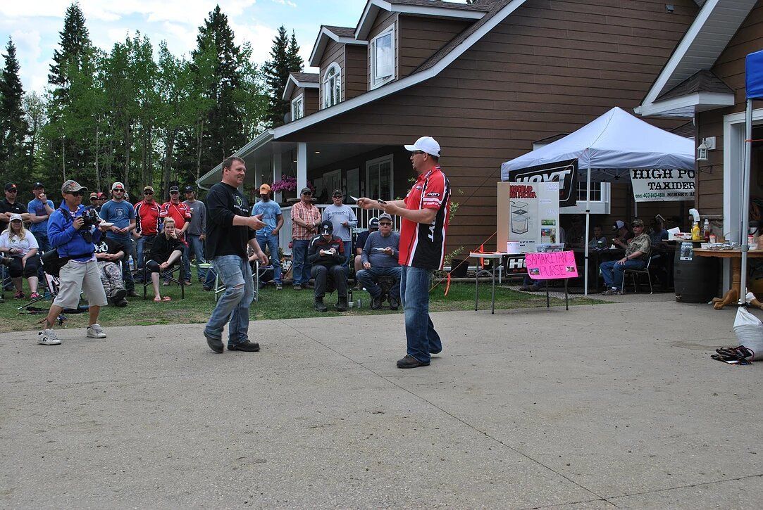 A man in a red and white shirt stands in front of a group of people