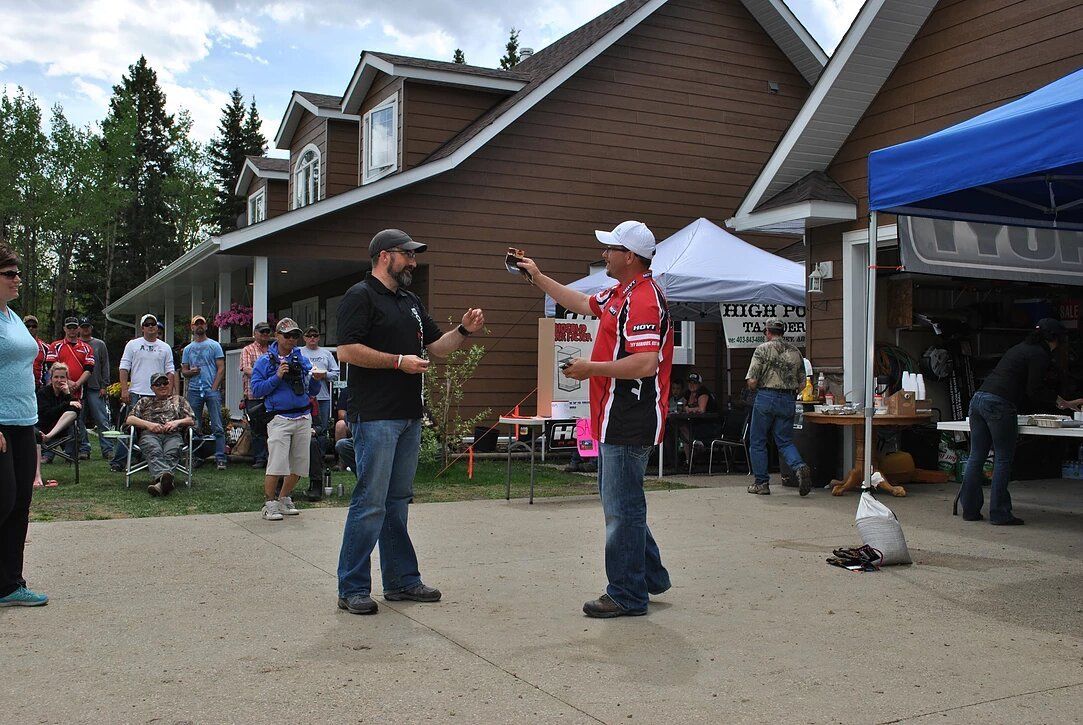 Two men are standing in front of a house talking to each other.