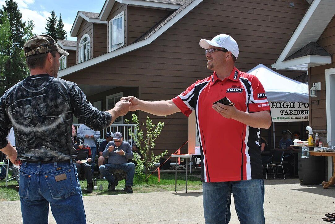 A man in a red shirt is shaking hands with another man