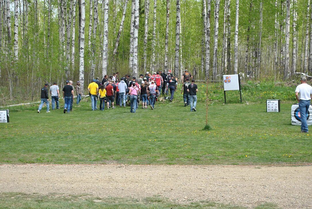 A group of people are standing in a field with trees in the background.
