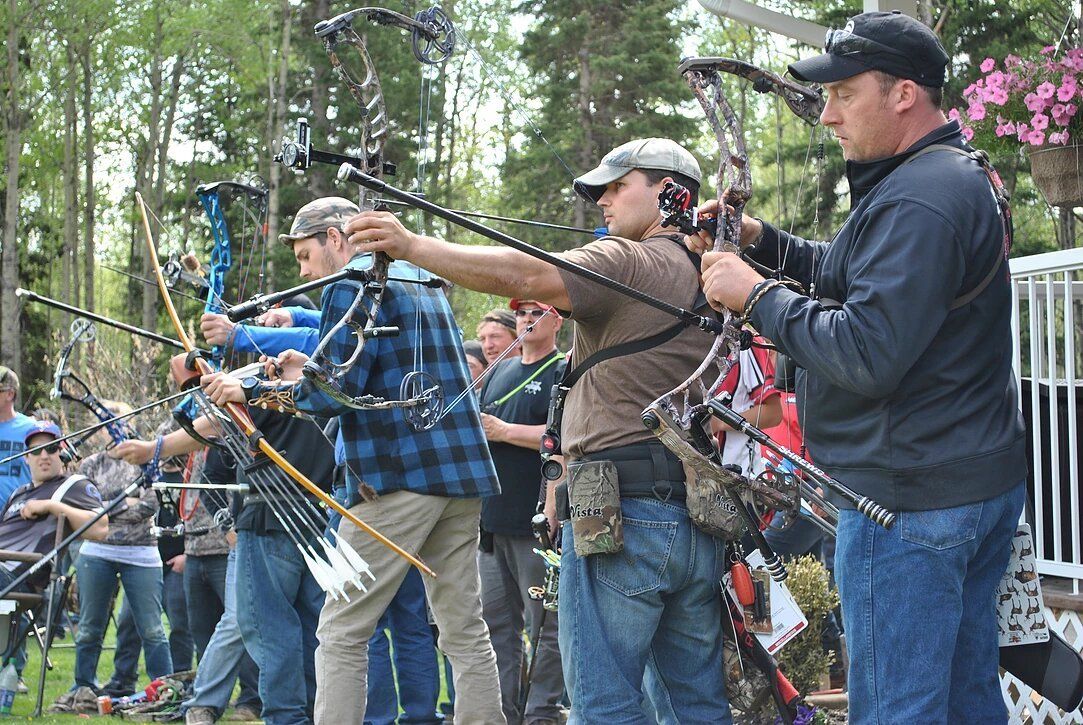A group of men are standing in a line holding bows and arrows.