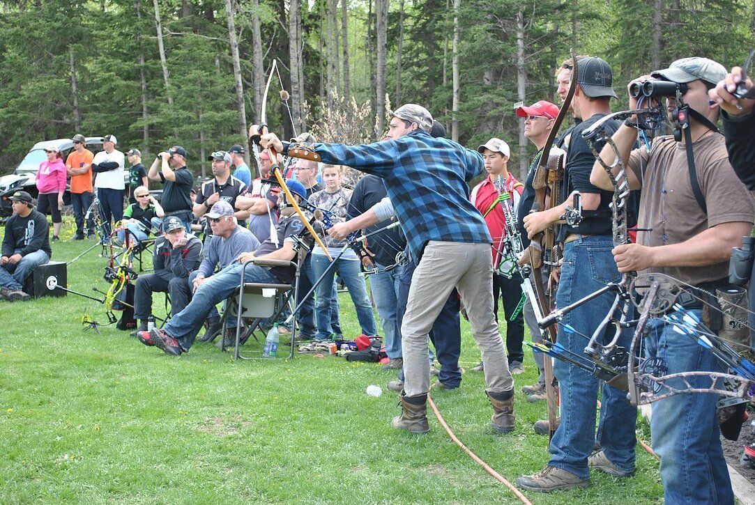 A group of people are standing in a field holding bows and arrows.