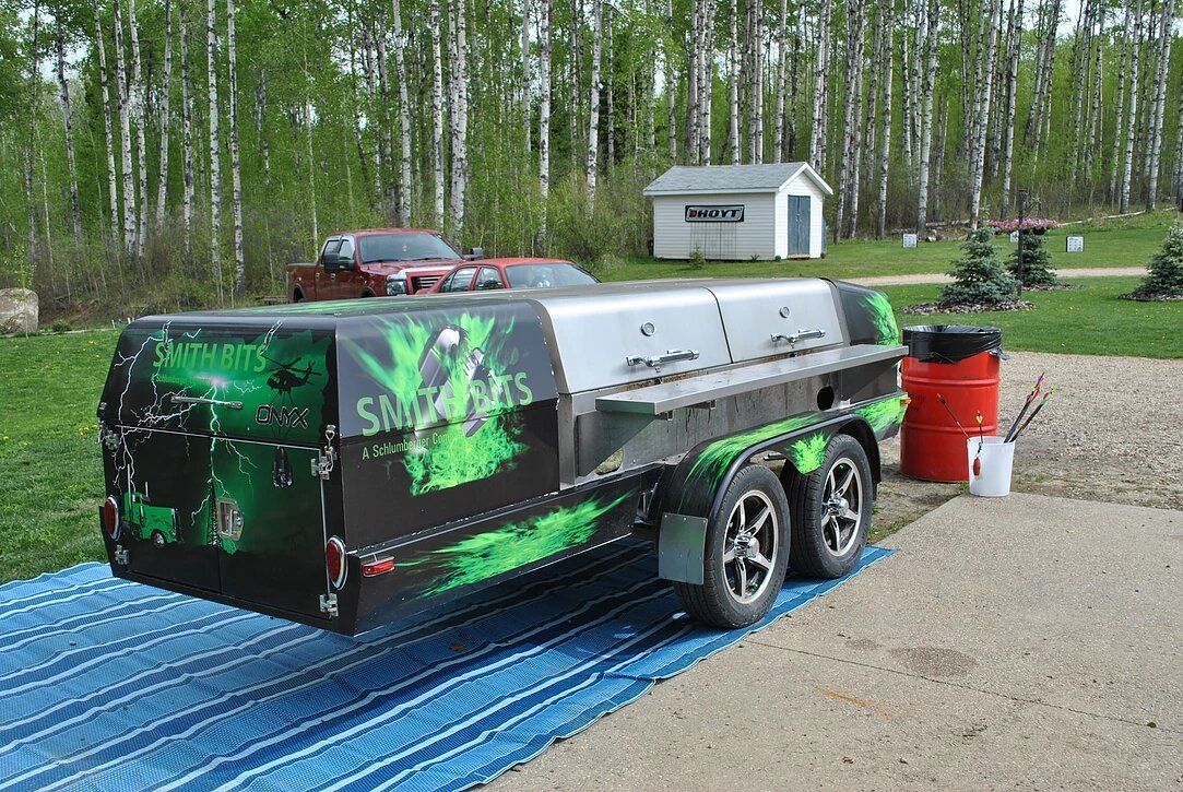 A green and black trailer is parked on a blue tarp.