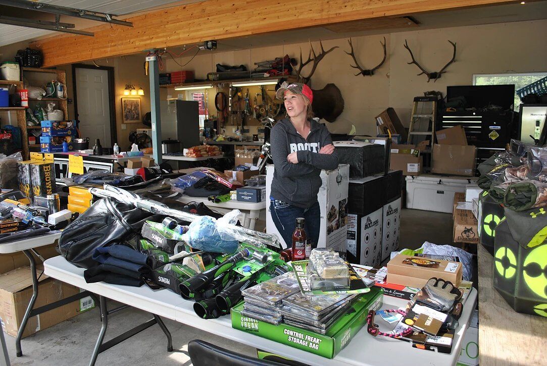 A woman is standing in front of a table filled with lots of items.