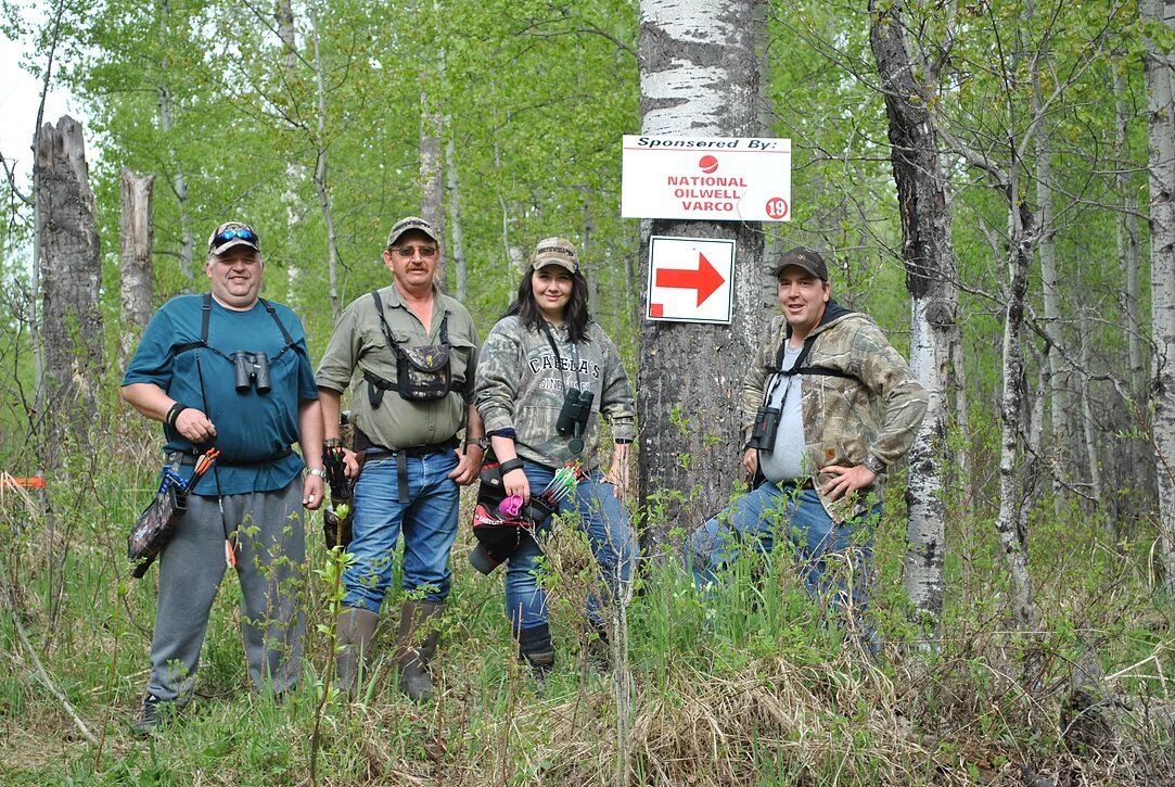 A group of people are posing for a picture in the woods.