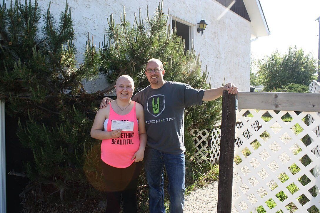 A man and a woman are posing for a picture in front of a house