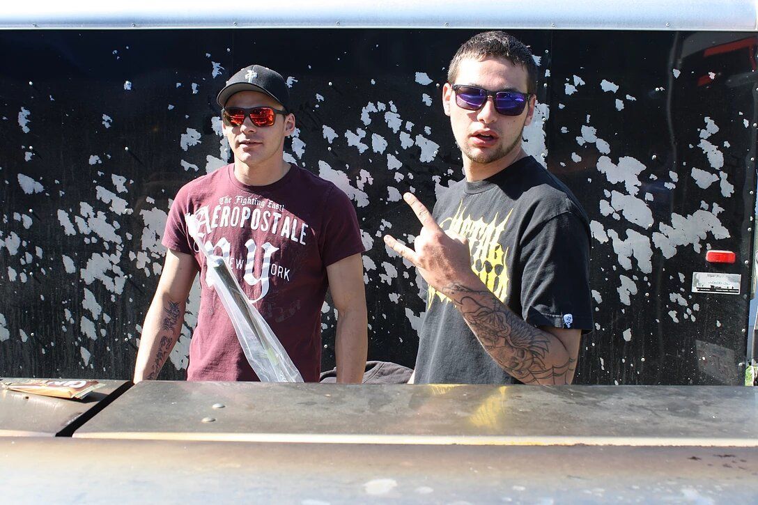 Two men standing next to each other with one wearing a trophy shirt