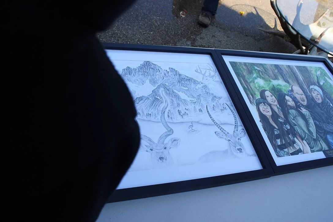 A group of paintings are sitting on a table with a person standing in the background