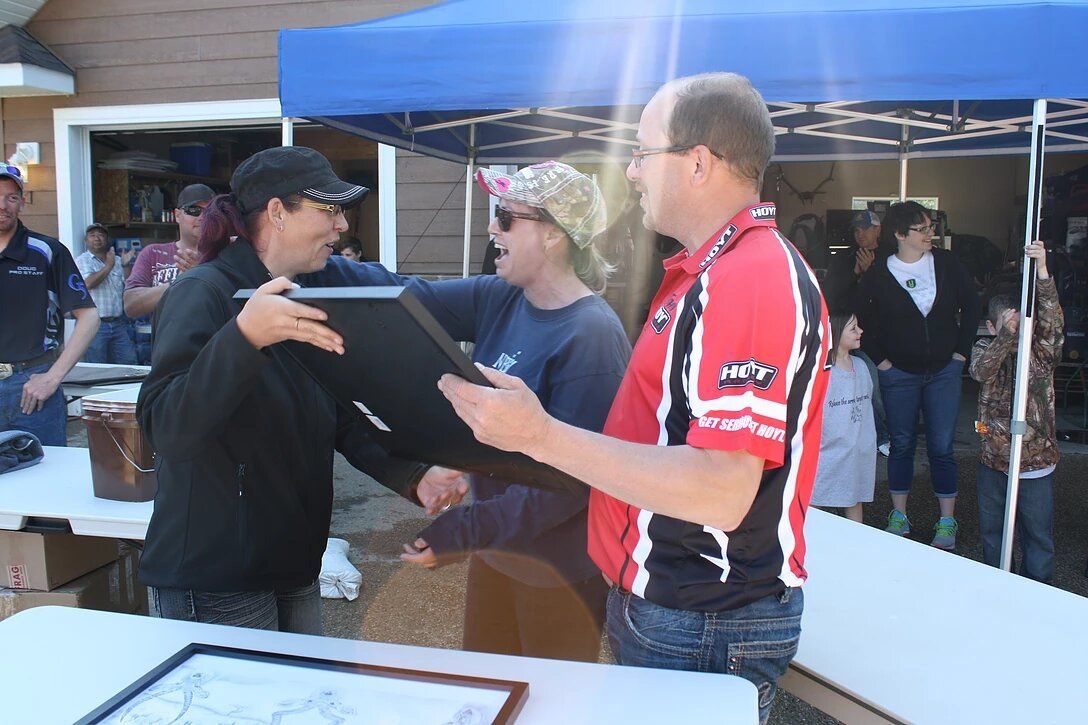 A man in a red and white shirt is shaking hands with another man