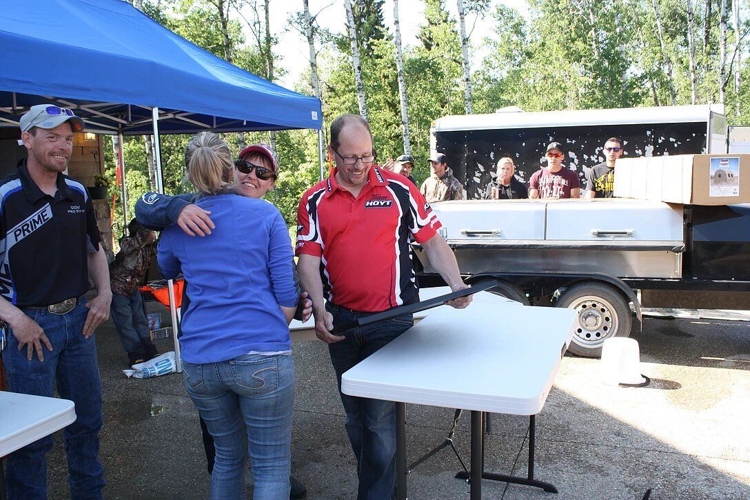 A man in a red shirt is carrying a white table