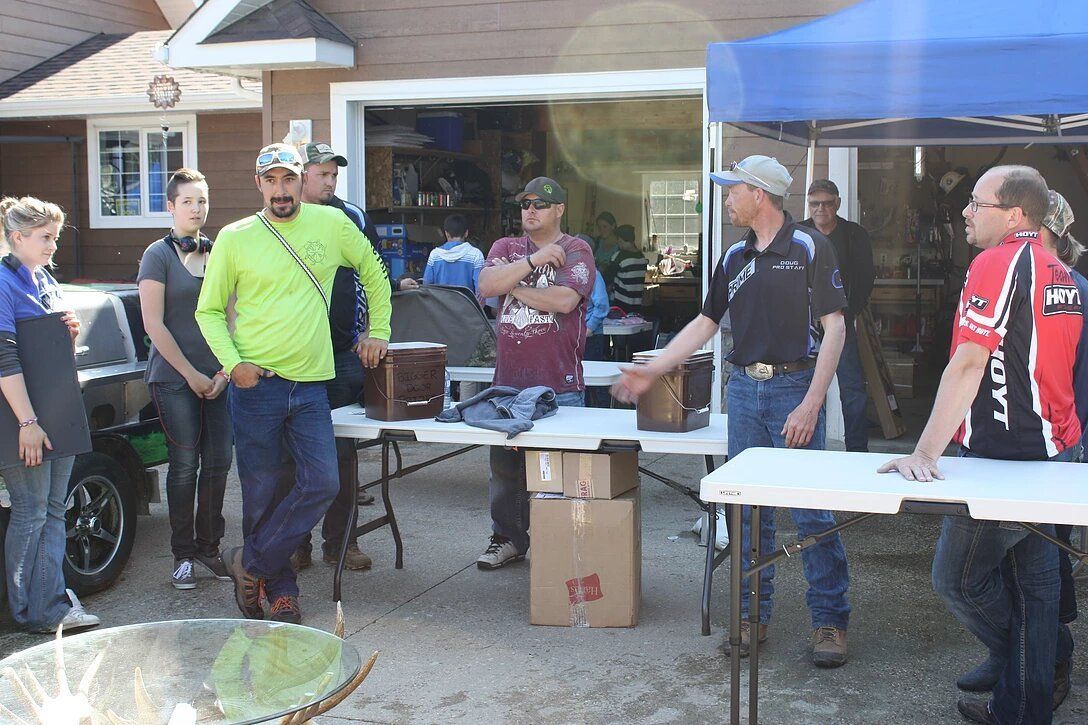 A group of people are standing around tables in front of a house.