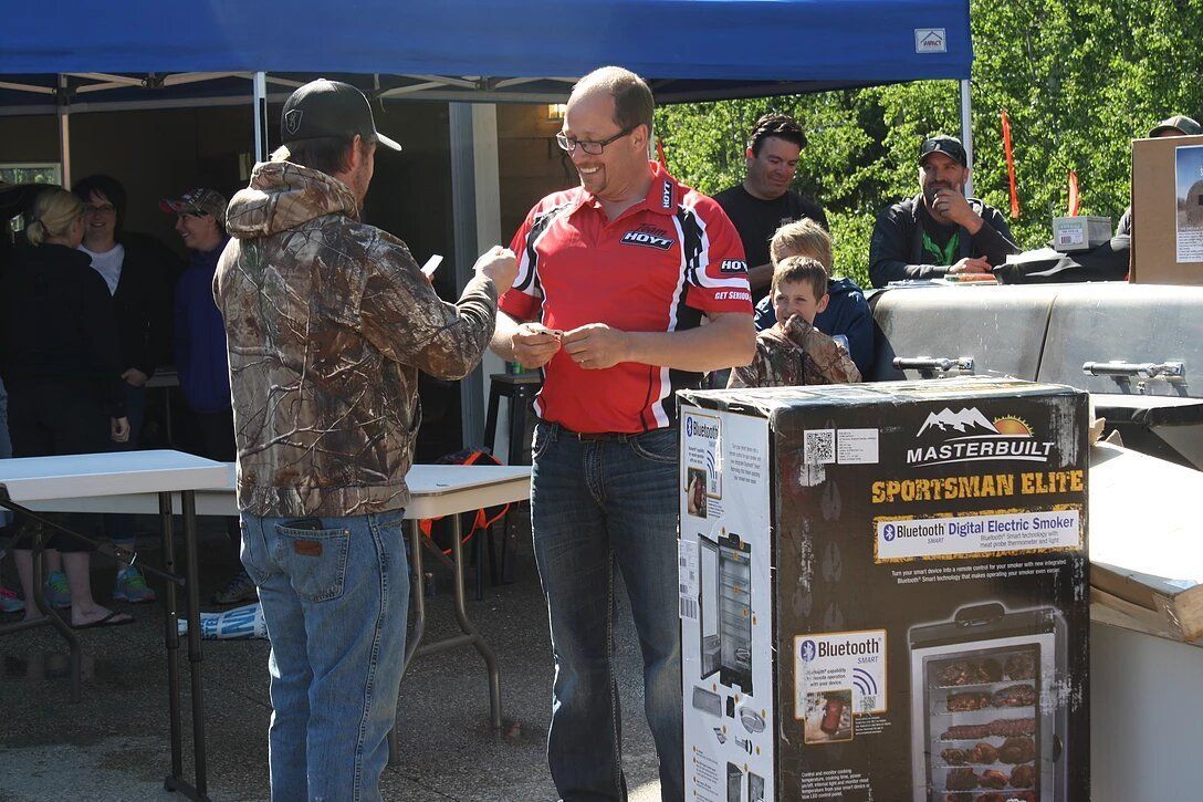 A man in a red shirt is shaking hands with another man