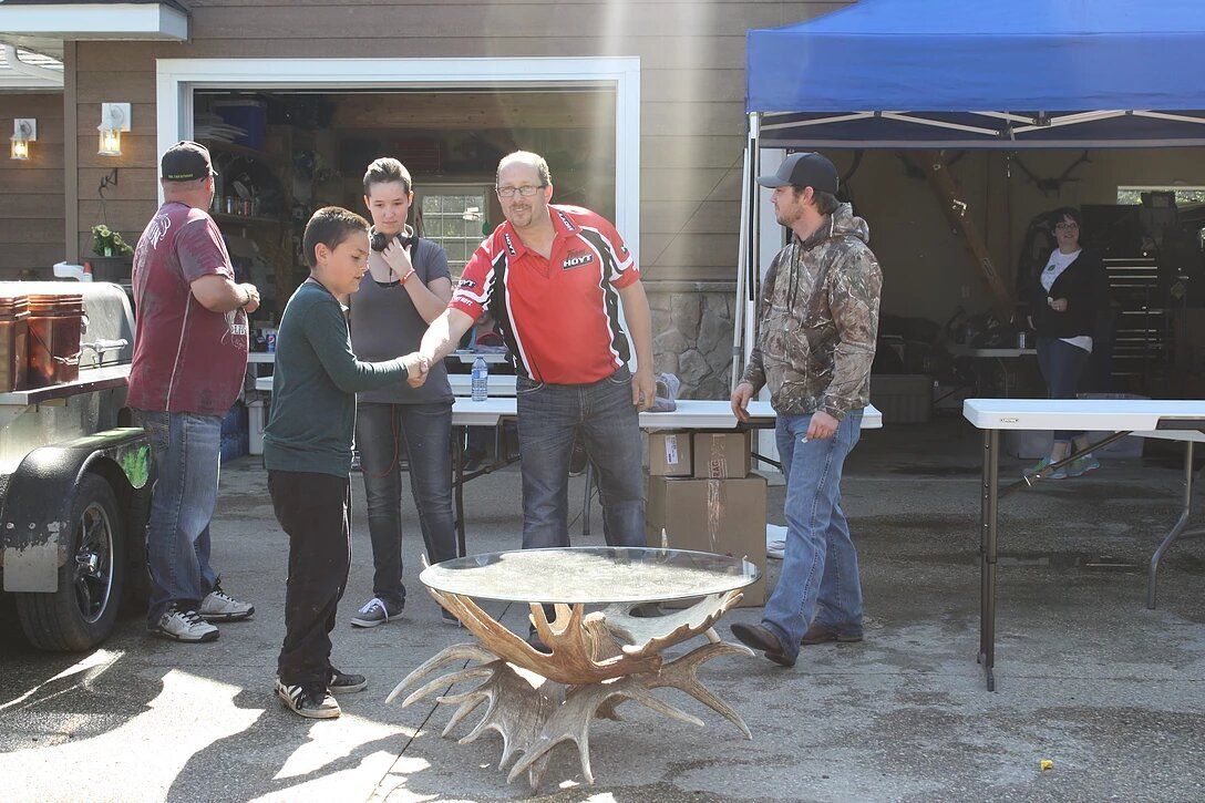 A group of people standing around a wooden table