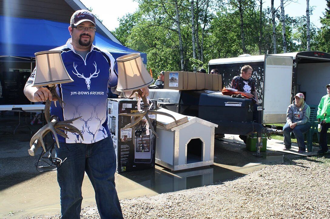 A man in a blue shirt is holding a pair of deer antlers.