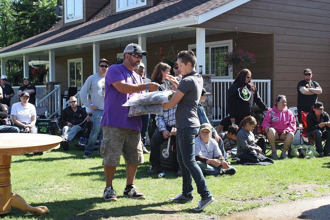 A man in a purple shirt is giving a woman a bag of food.