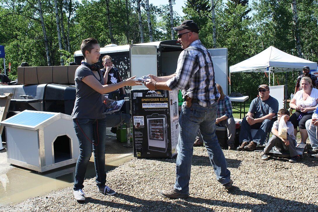 A man and a woman are standing next to each other in front of a dog house.